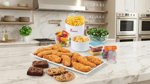 Family meal spread of chicken strips, fries, sides and cookies, the hero image from chickfilamenu.net