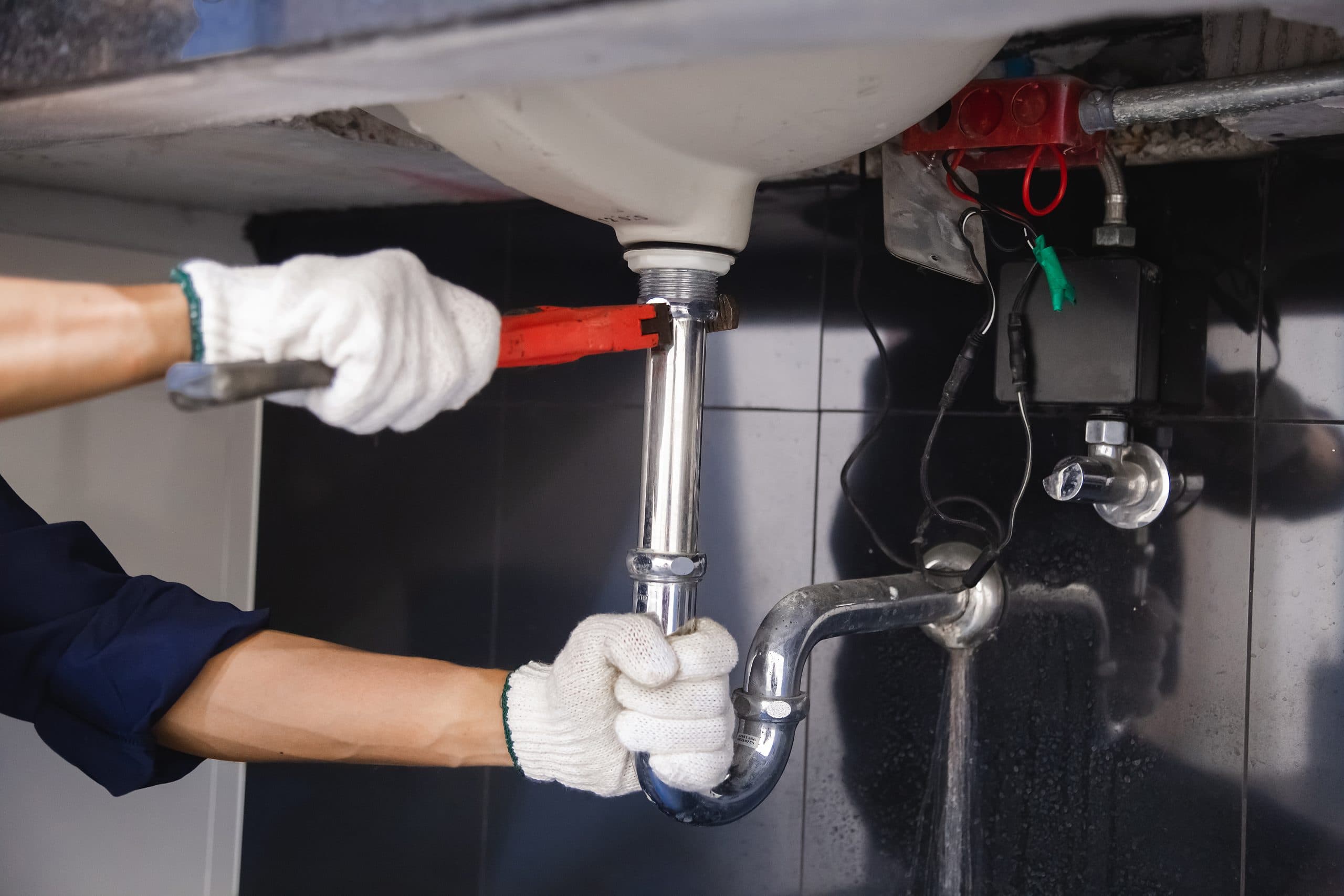 Plumber fixing a sink pipe with an adjustable wrench