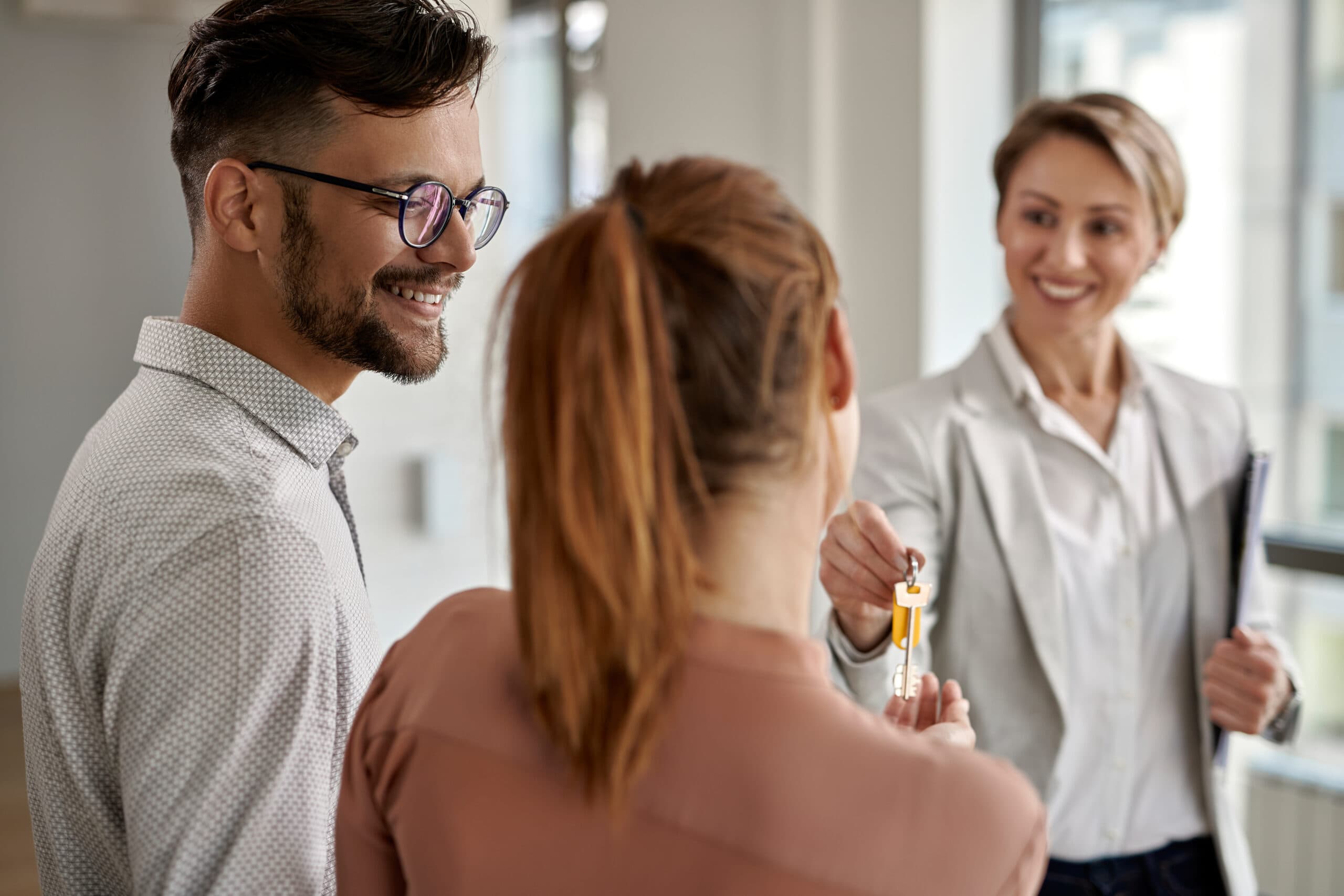 Real estate agent handing a house key to a smiling couple