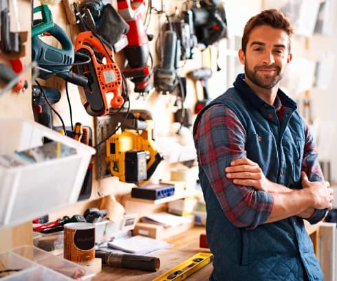 Tradesman standing in his workshop in front of his tools