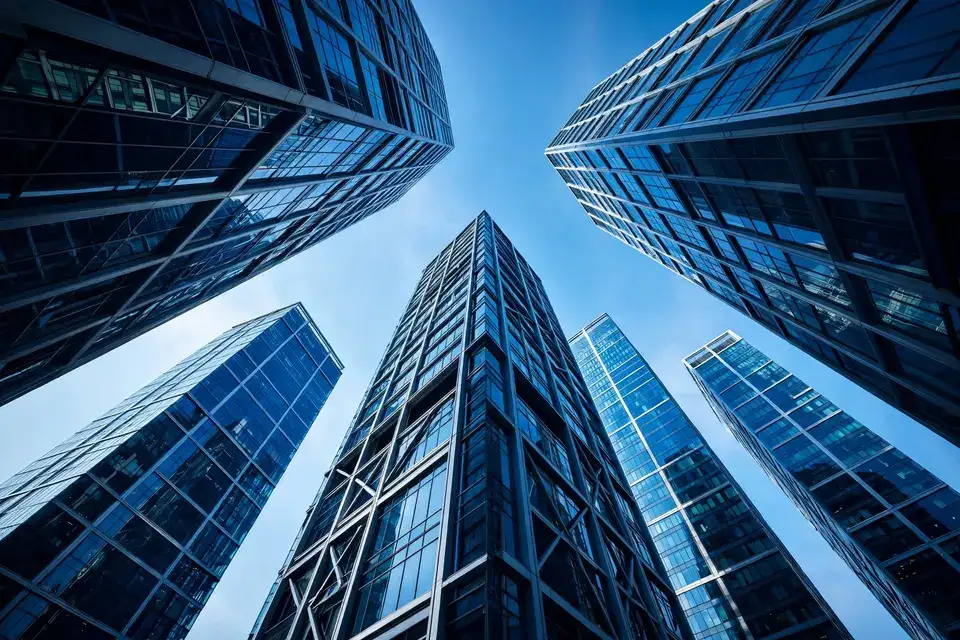 Modern glass office towers seen from below against a blue sky